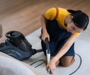 Young Asian woman using vacuum cleaner at home. floor in an apartment with a vacuum cleaner..